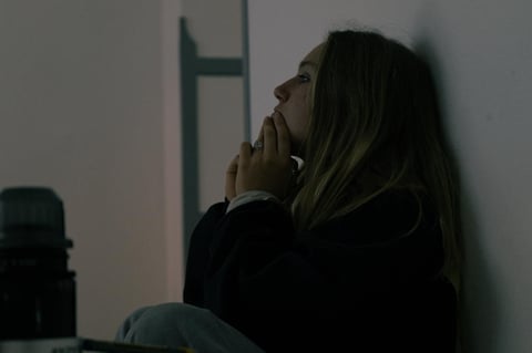 Person mit dunklen Haaren vor einer grauen Wand